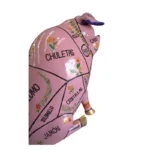 Estatua de cerdo rosado con mapa de cortes de carne en español y flores estilo mexicano.